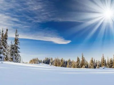 A field covered in snow with the sun in the blue sky