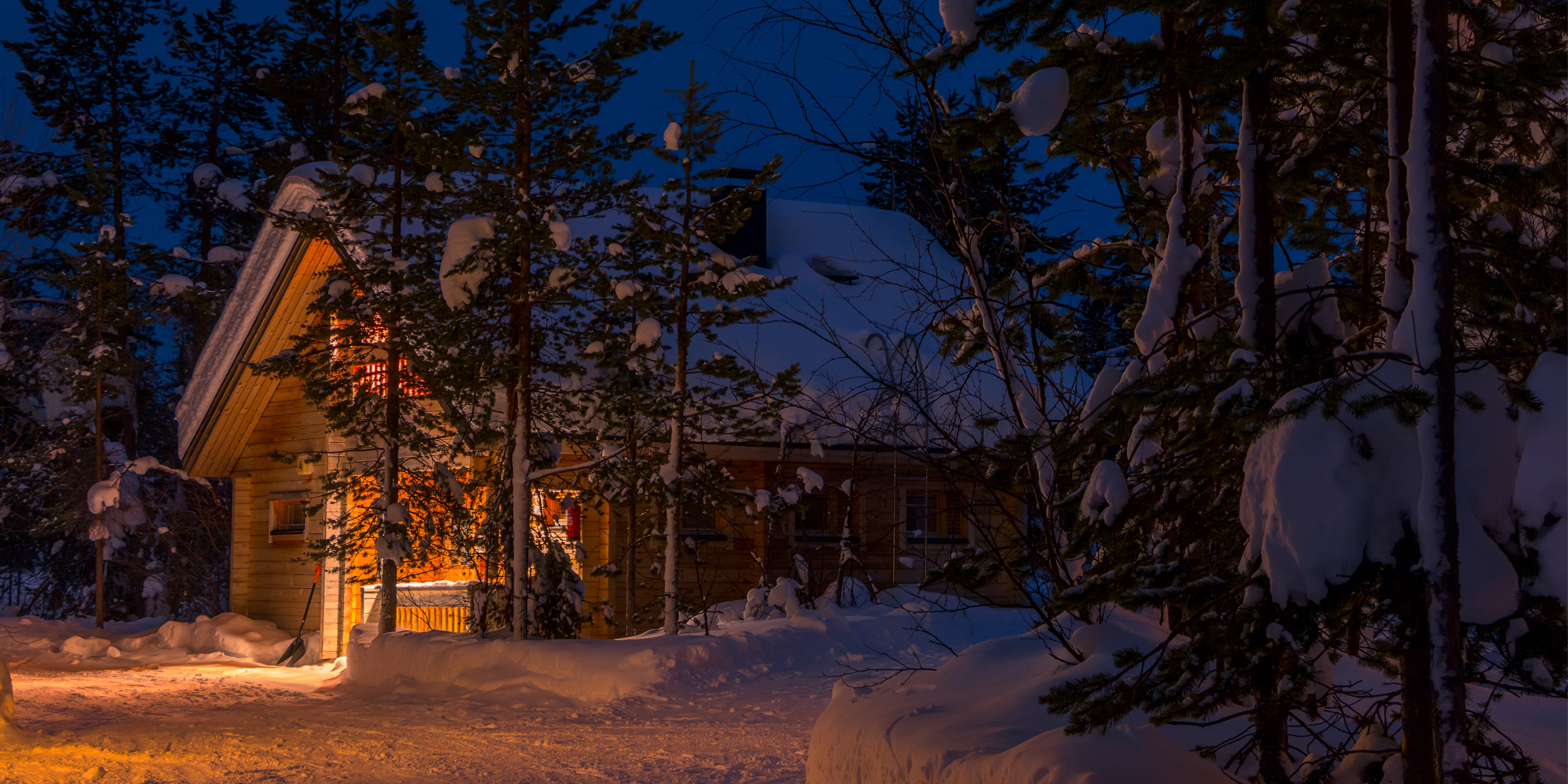 House covered in snow and surrounded by trees