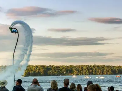 Hovering water board at a lake with lots of people watching